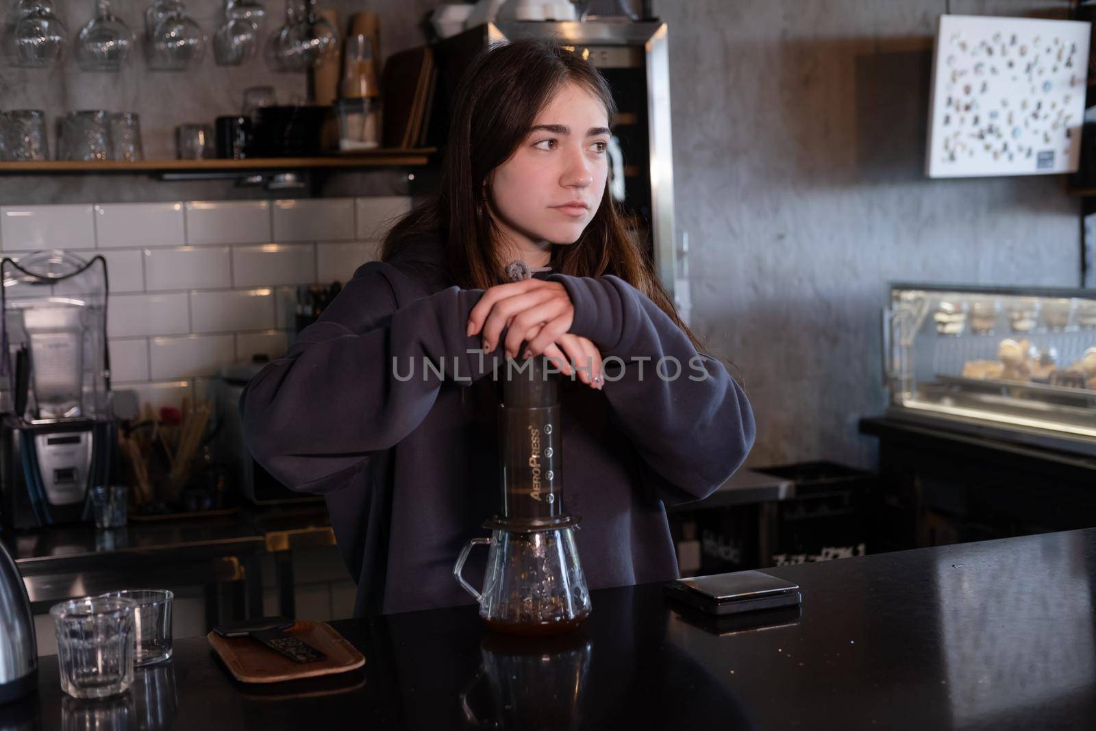 pretty brunette girl making aeropress coffee in modern coffee shop.