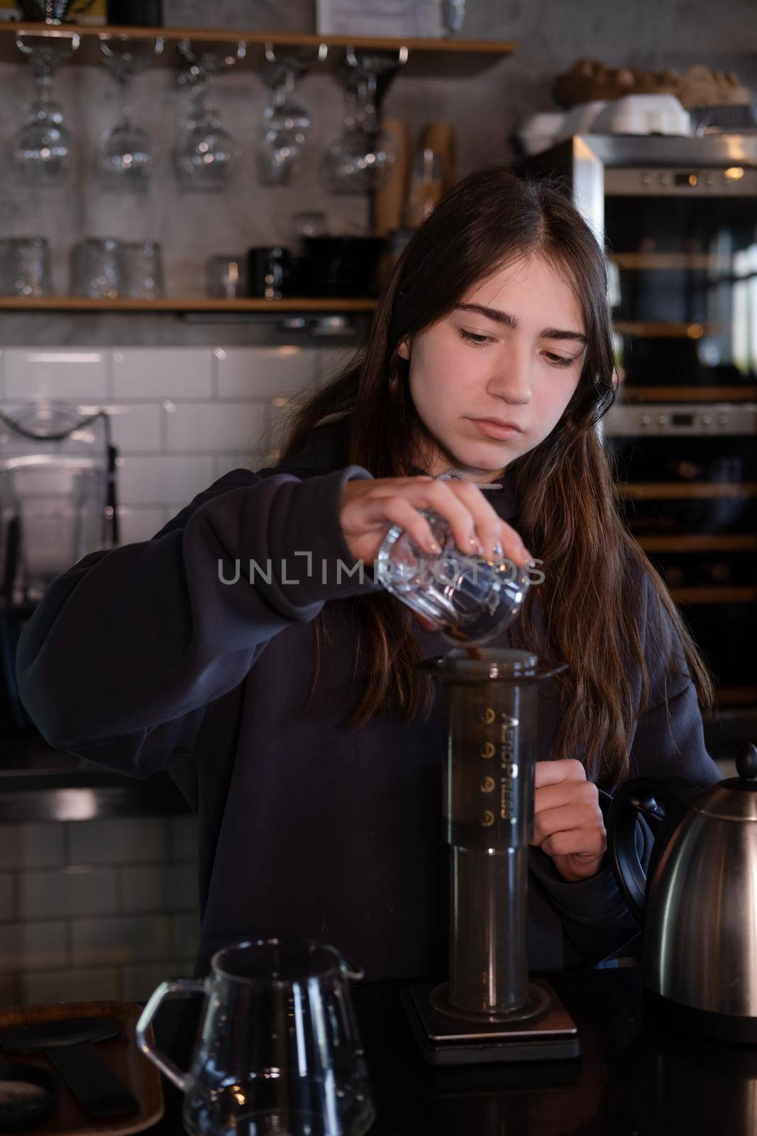 pretty brunette girl making aeropress coffee in modern coffee shop.