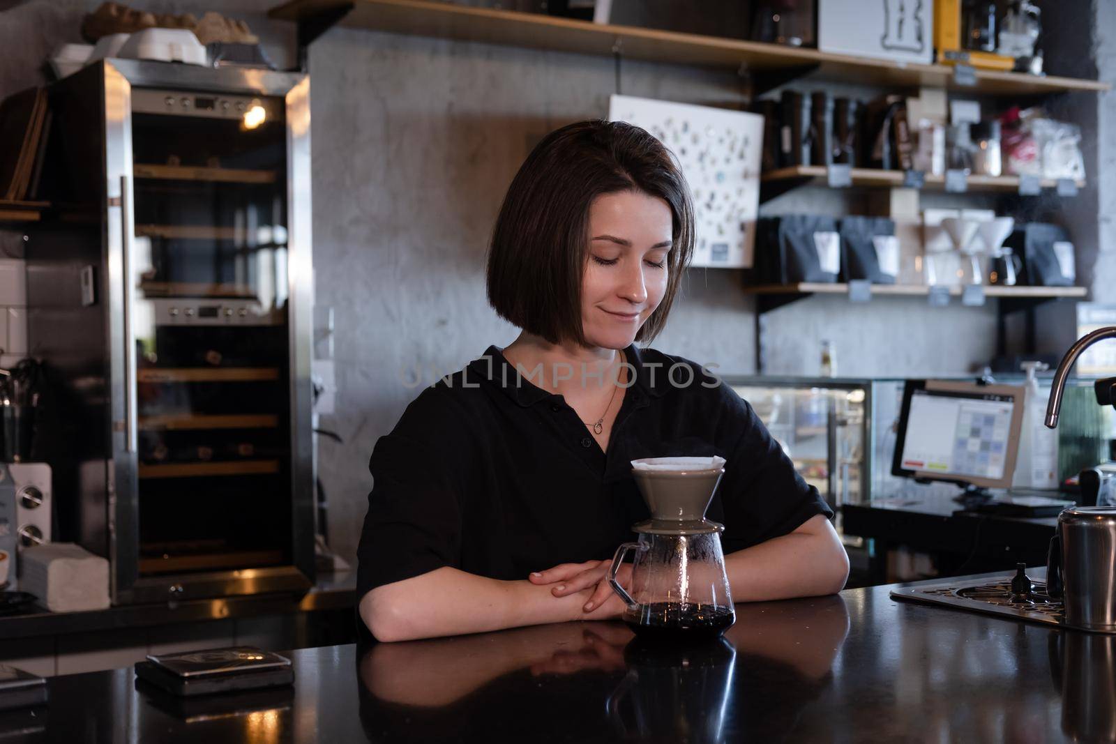 charming brunette woman barista making filter coffee in coffee shop. brewing coffee in cafe.