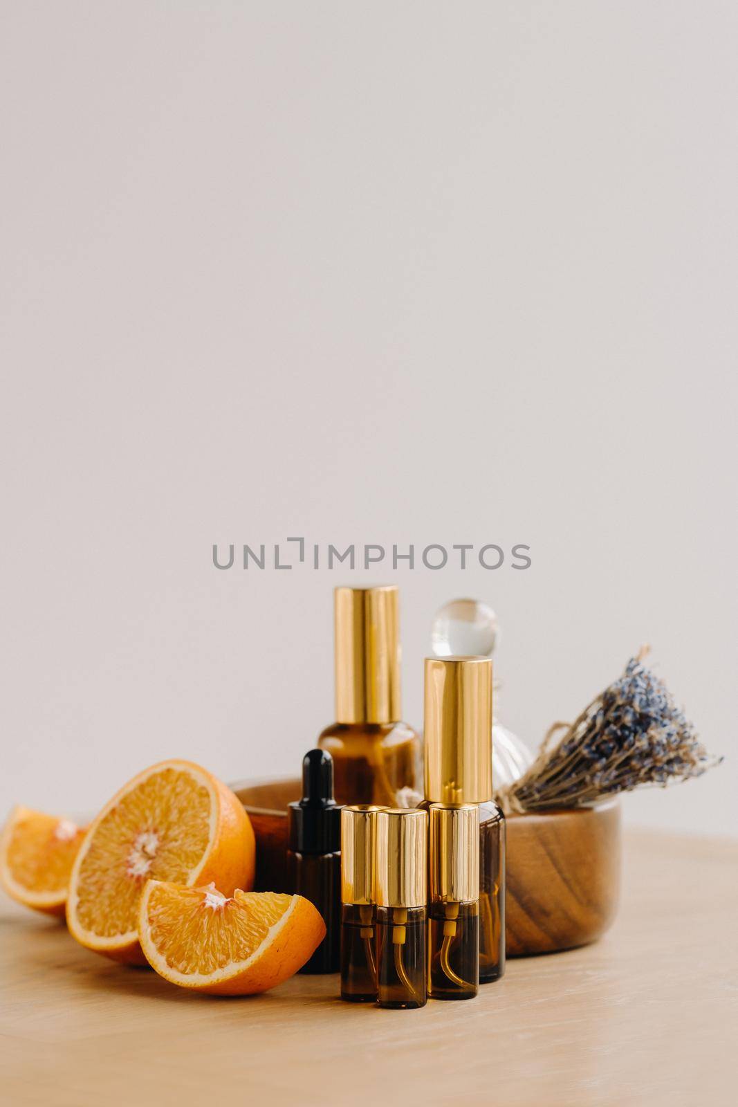 Essential oil in bottles with the aroma of orange and lavender lying on a wooden surface by Lobachad