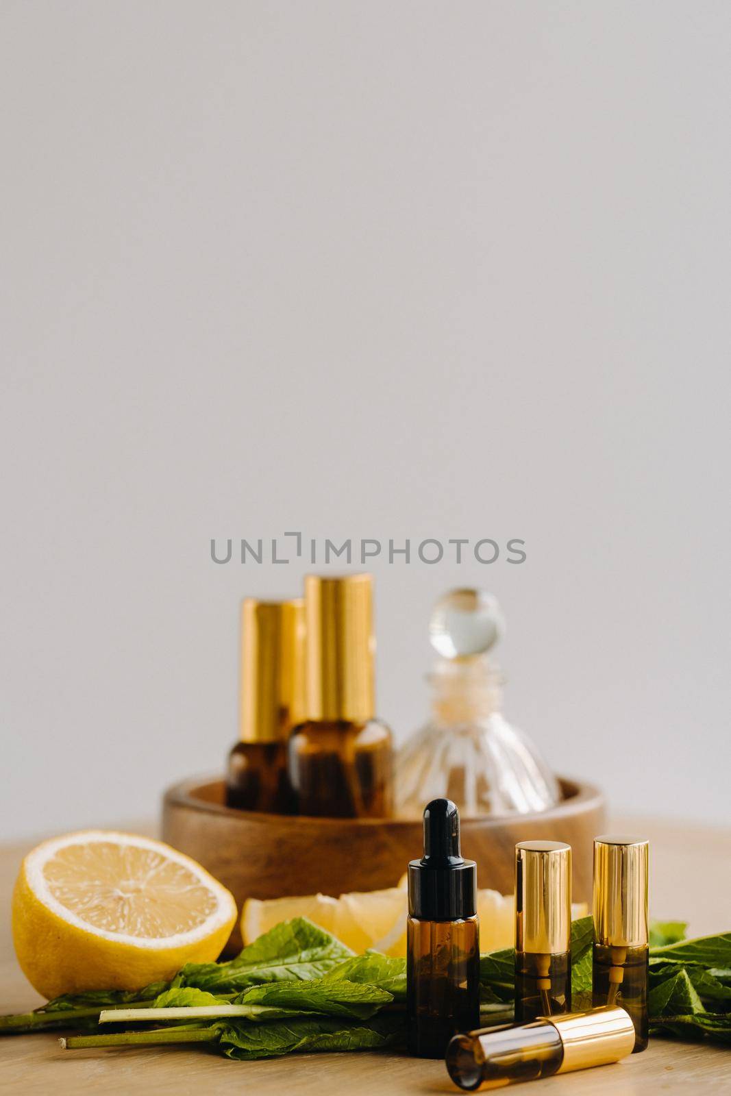 Essential oil in bottles with lemon and mint fragrance lying on a wooden surface.