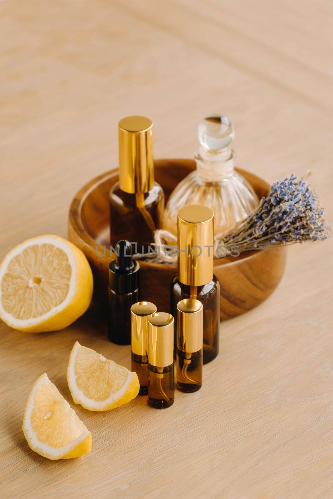 Essential oil in bottles with lemon and lavender fragrance, lying on a wooden surface by Lobachad