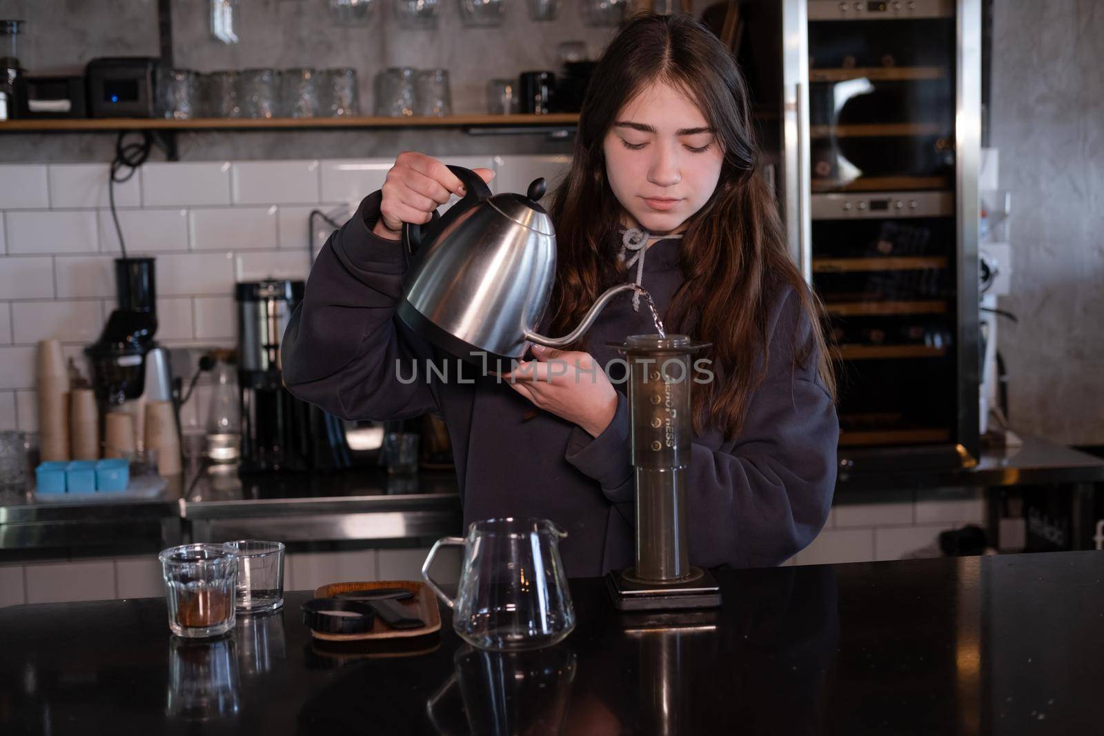 pretty brunette girl making aeropress coffee in modern coffee shop.