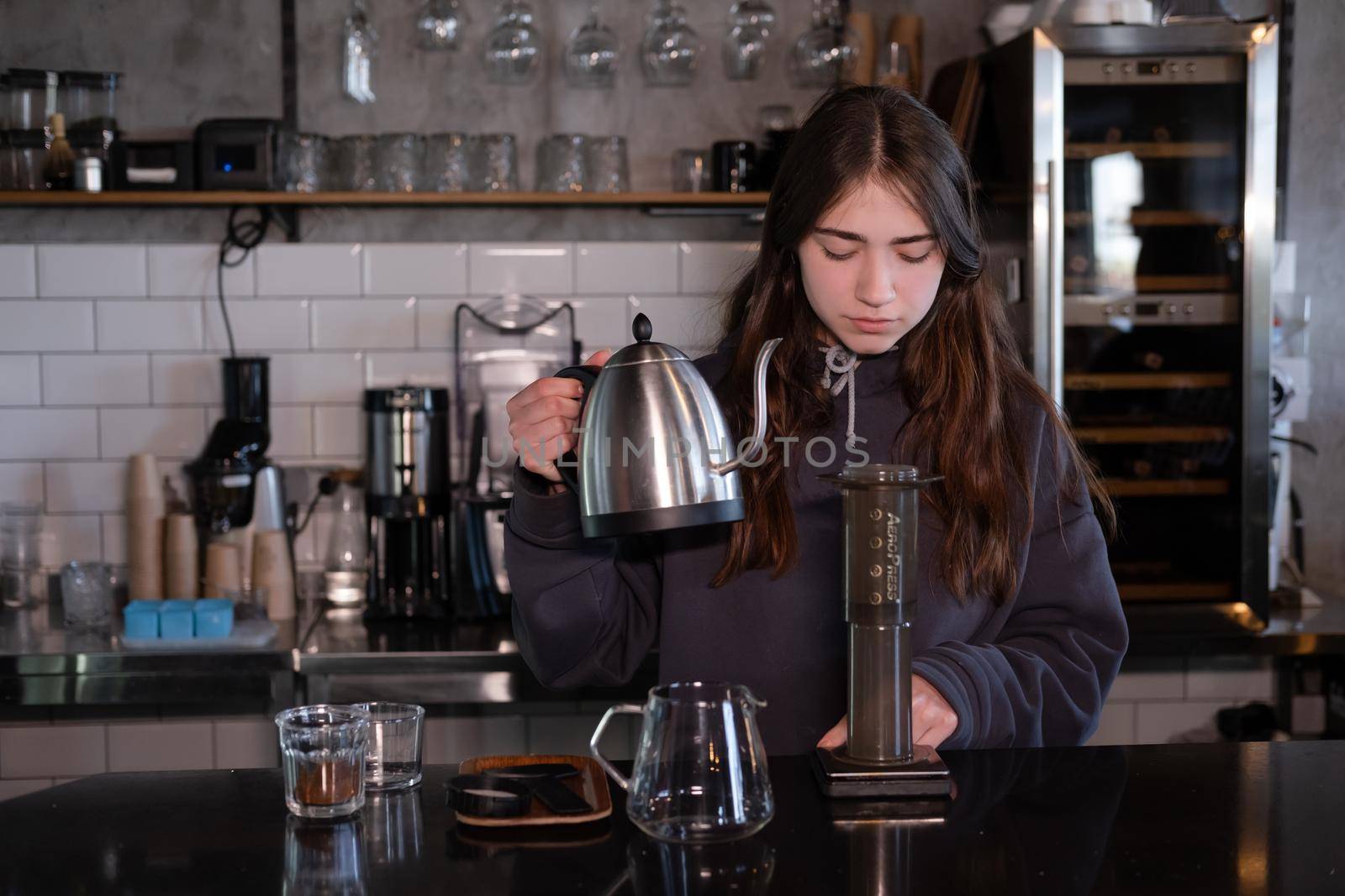 pretty brunette girl making aeropress coffee in modern coffee shop.