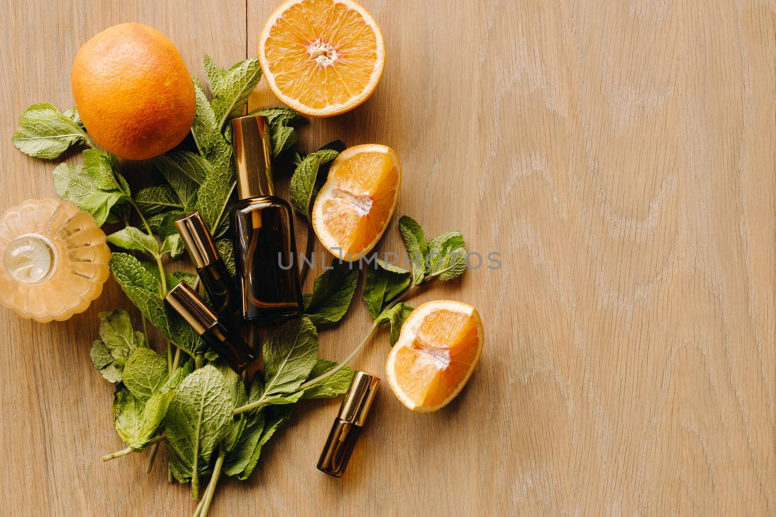 Essential oil in bottles with the aroma of orange and mint lying on a wooden surface.