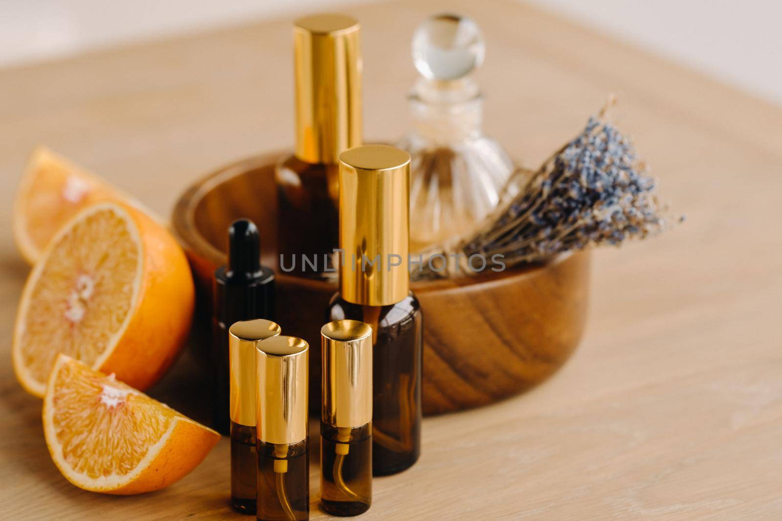 Essential oil in bottles with the aroma of orange and lavender lying on a wooden surface.