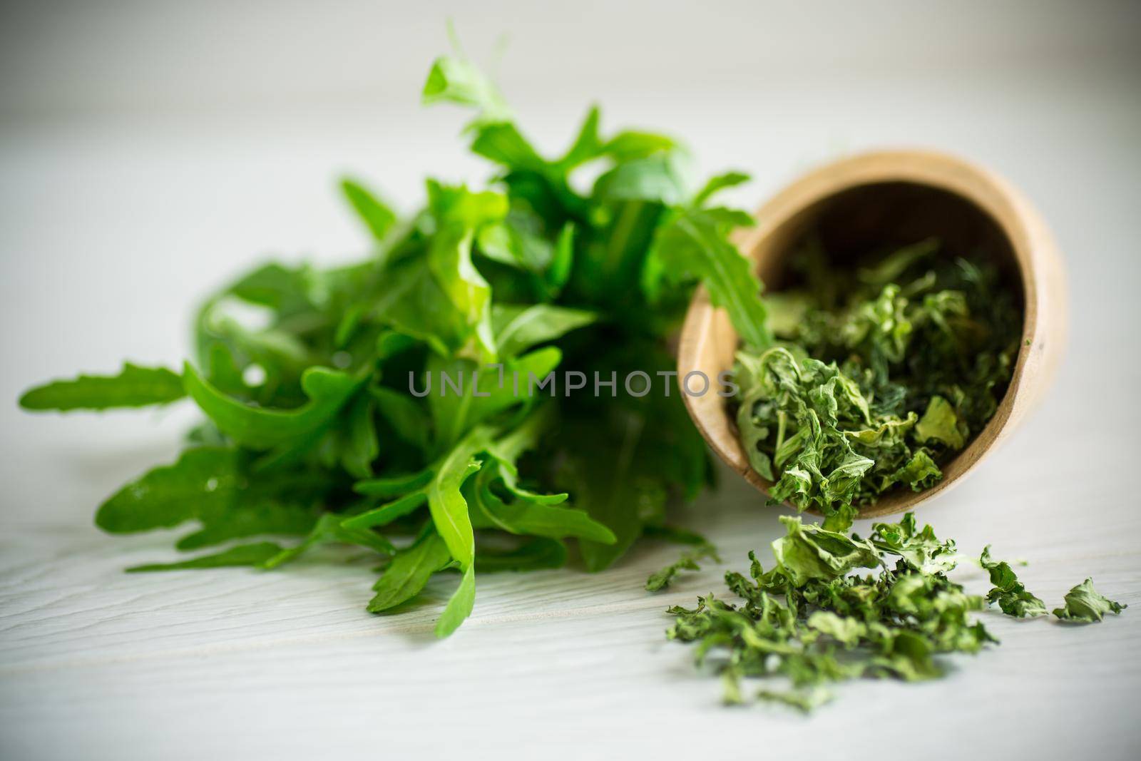 dried green organic arugula, seasoning, on a light wooden background