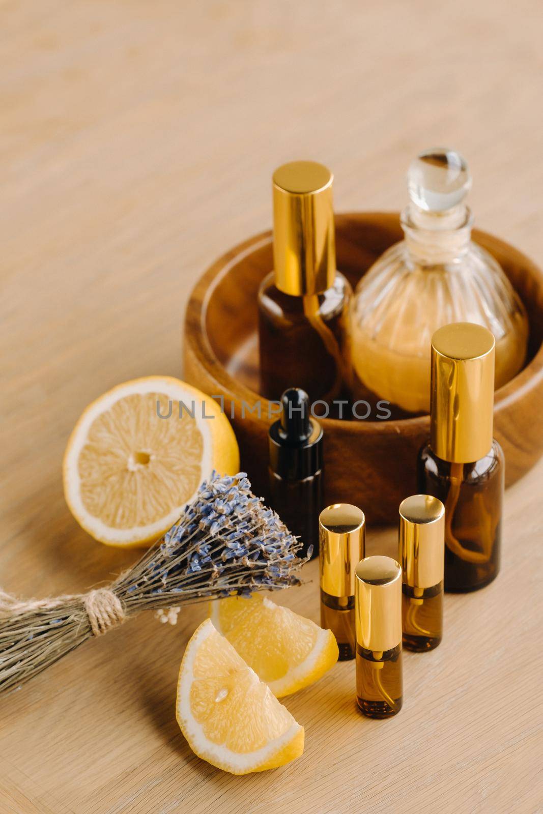 Essential oil in bottles with lemon and lavender fragrance, lying on a wooden surface.