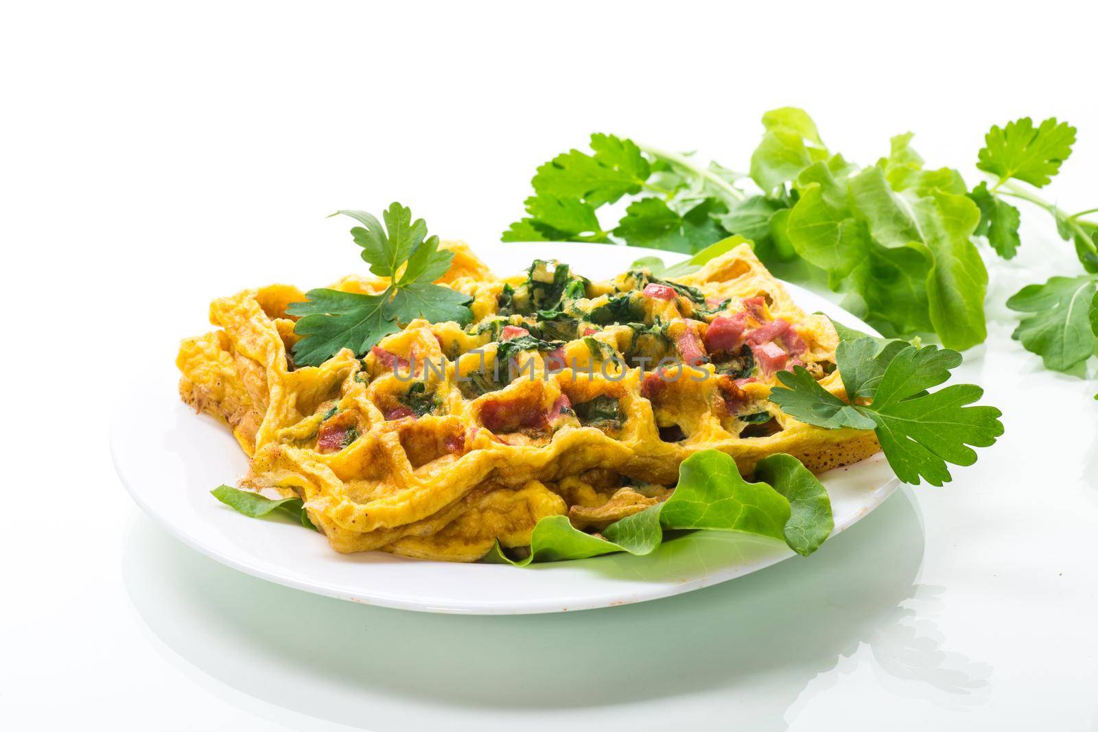 Egg omelet stuffed with greens and sausage fried in the form of waffles, isolated on white background