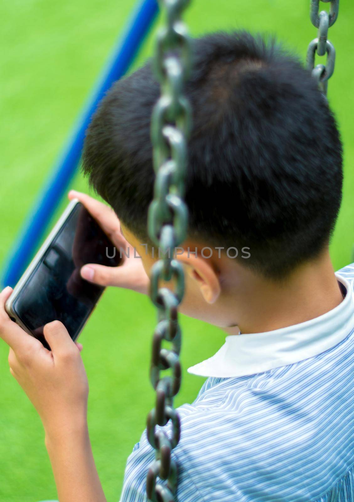 Asian boy playing game on smart phone by Satakorn