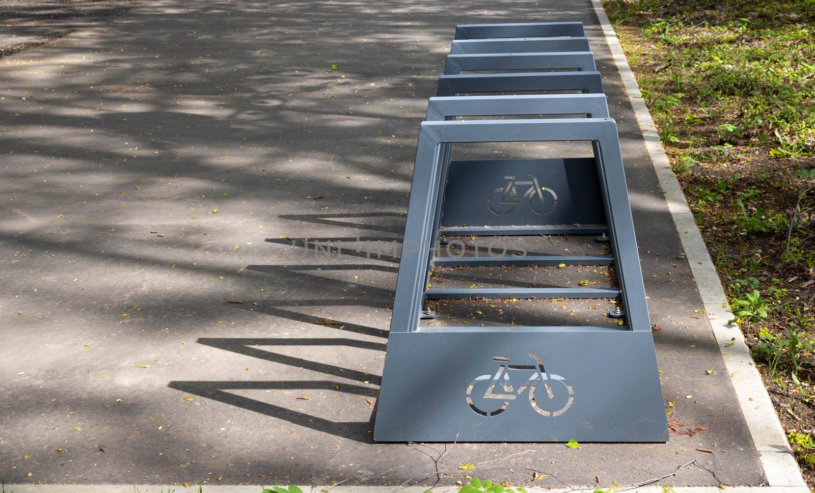 An empty metal bicycle rack on an alley in a city park.