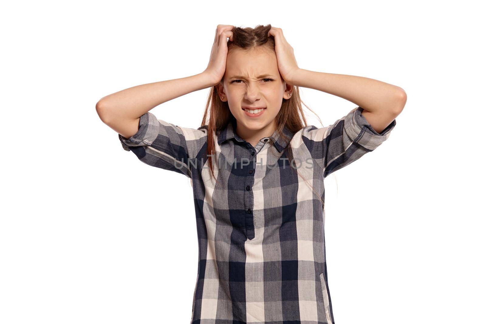 Portrait of a gorgeous teenage female in a casual checkered shirt acting like has a headache while posing isolated on white studio background. Long hair, healthy clean skin and brown eyes. Sincere emotions concept. Copy space.