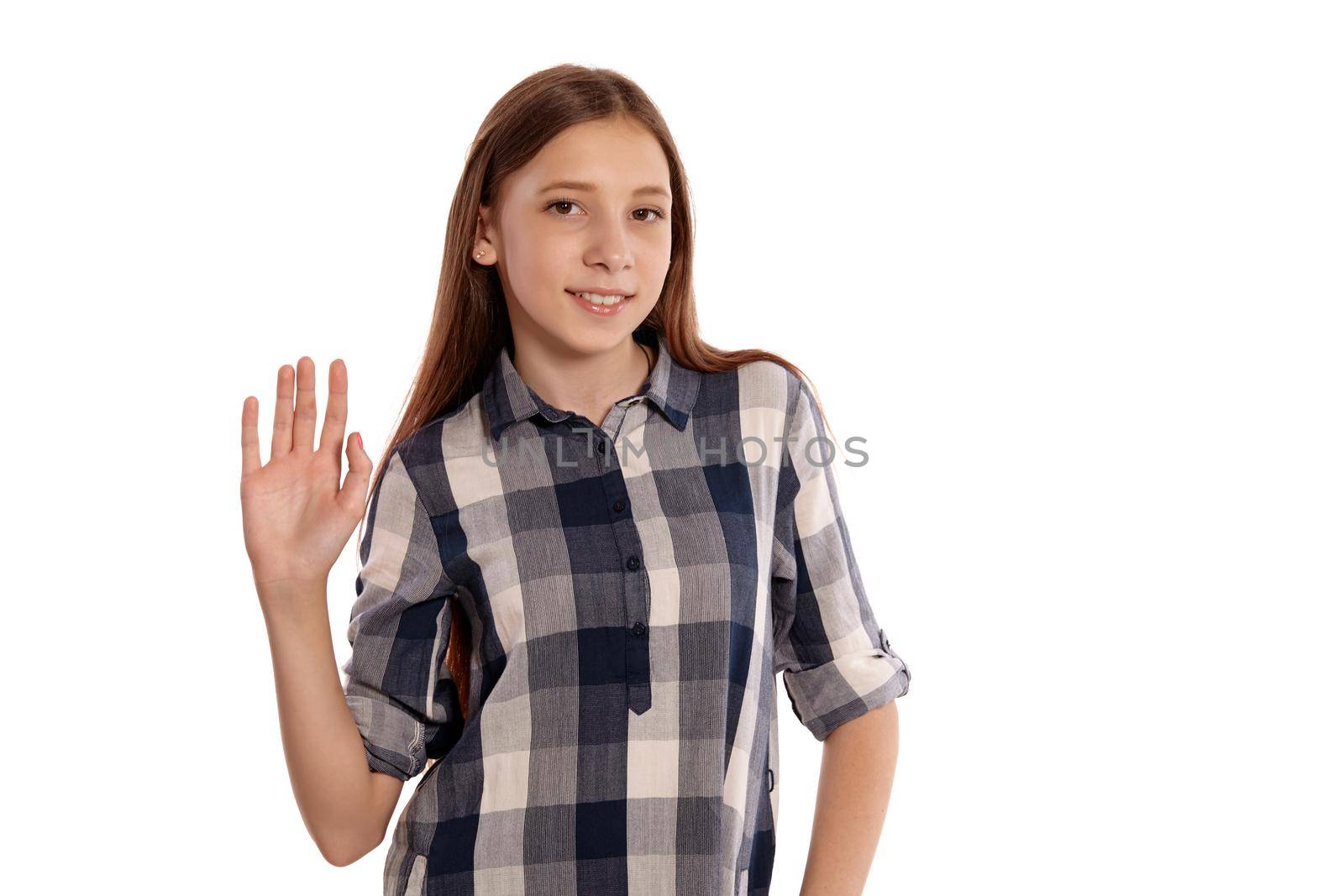 Portrait of a charming teenage female in a casual checkered shirt saying hi to you and posing isolated on white studio background. Long hair, healthy clean skin and brown eyes. Sincere emotions concept. Copy space.