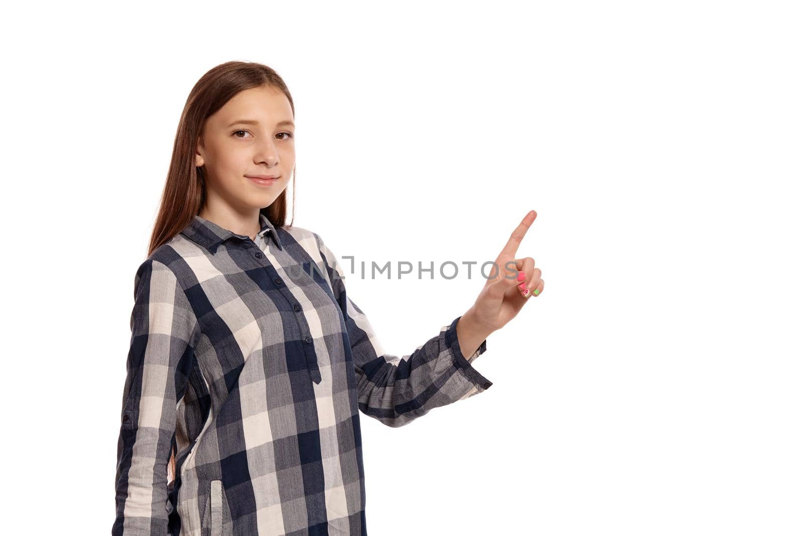 Portrait of a cute teenager in a casual checkered shirt gesticulating while posing isolated on white studio background. Long hair, healthy clean skin and brown eyes. Sincere emotions concept. Copy space.