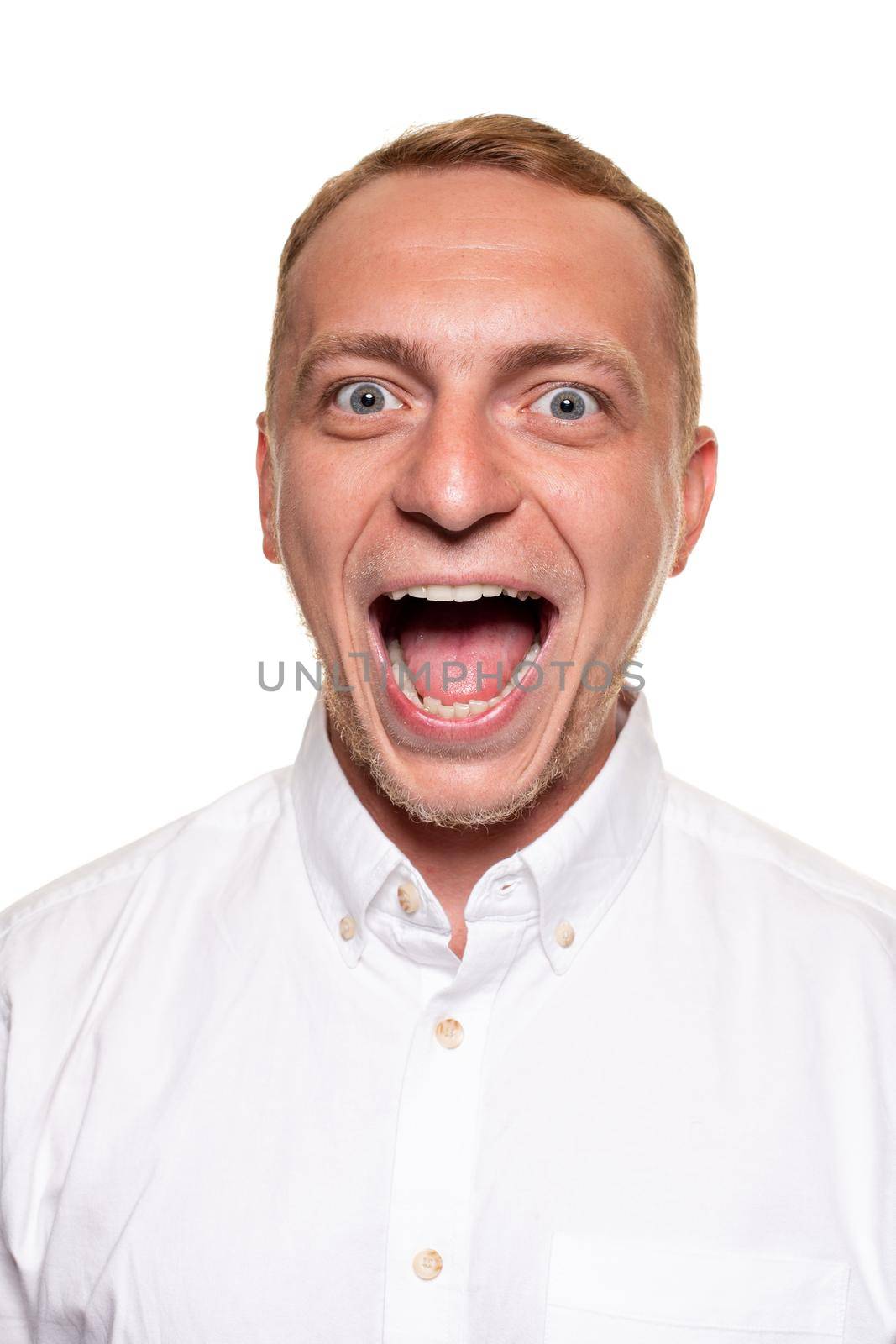 Handsome young blond man in a white shirt have opened his mouth, isolated on a white background