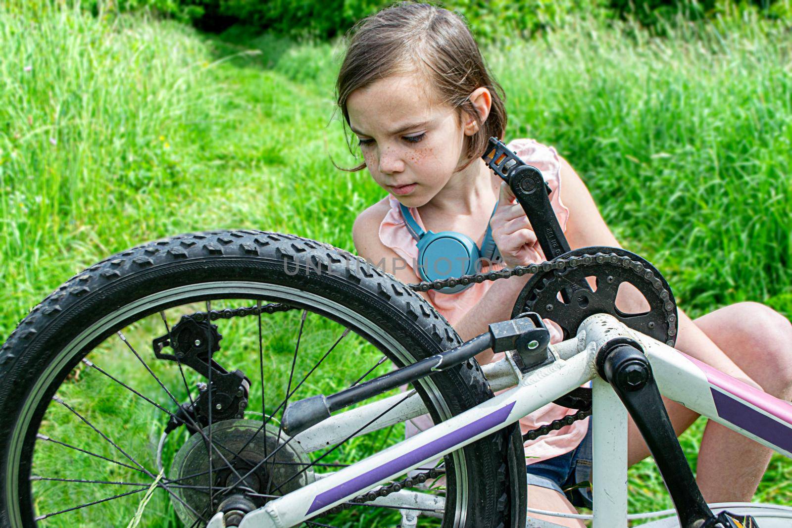 a child girl has damaged a bicycle wheel and is making repairs photo without processing. High quality photo