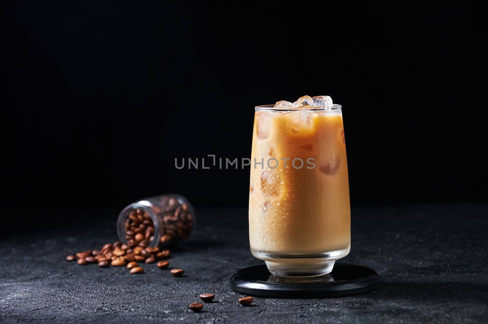 Iced Coffee with Milk in Tall Glass on Dark Background. Concept Refreshing Summer Drink.