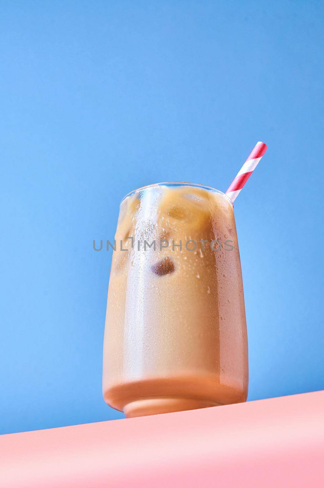Iced Coffee with Milk in Tall Glasses on Pink Table and Blue Background. Trendy Hero View by Svetlana_Belozerova