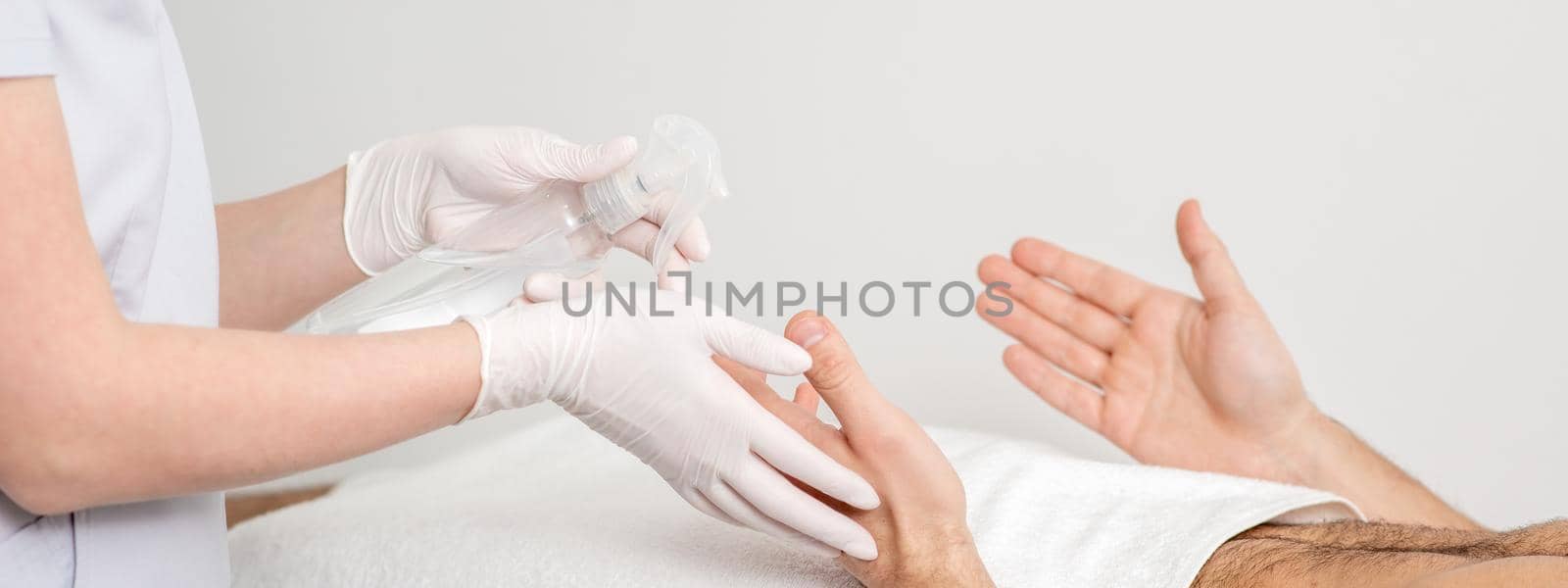 Nurse hand sanitizing hands of male patient in the hospital. Coronavirus protection concept.