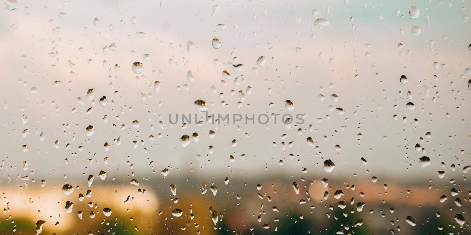 Drops of rain on the window. Rainy days in the city landscape. Defocused