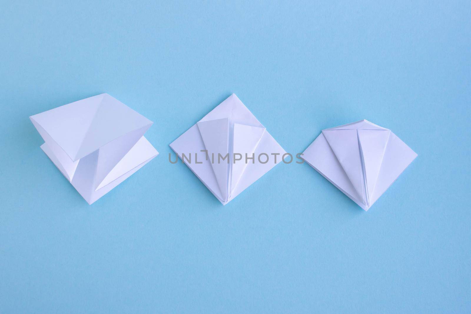 Handmade white trendy geometric polygonal paper origami fish on blue background.Step 2. Horizontal poster.