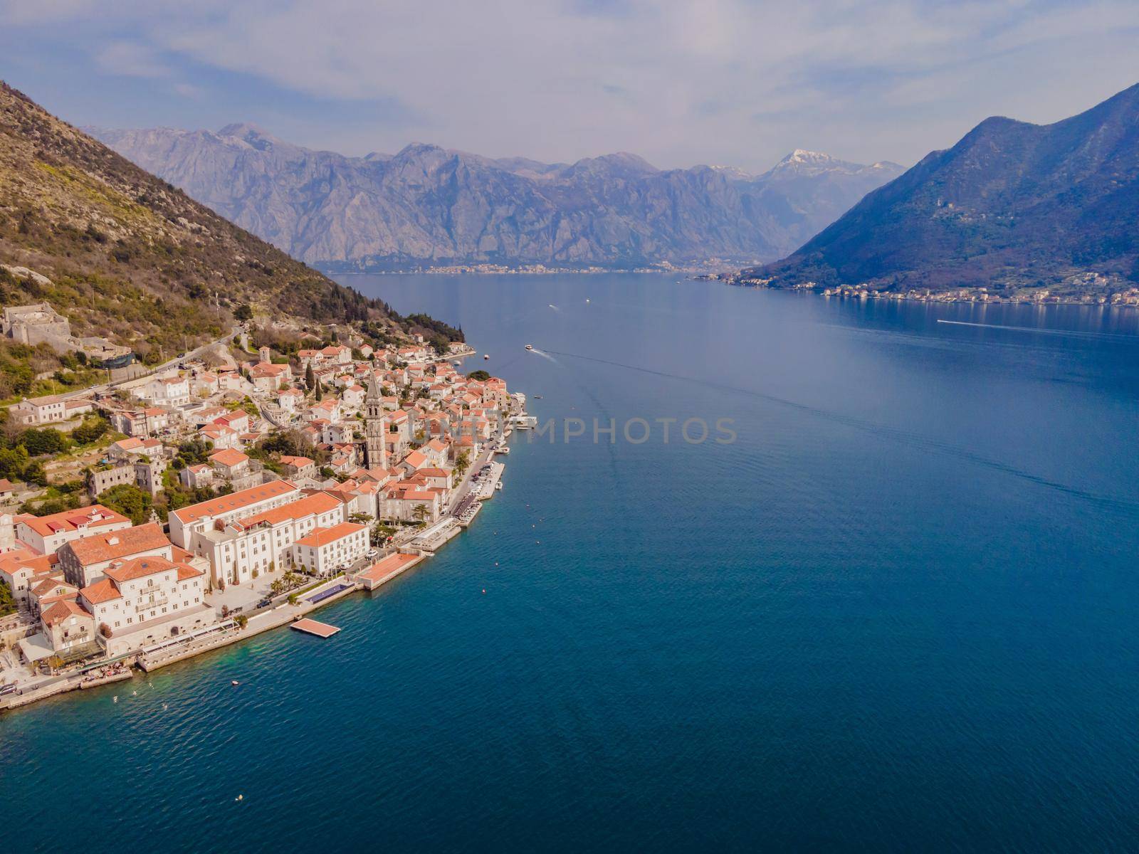 Scenic panorama view of the historic town of Perast at famous Bay of Kotor with blooming flowers on a beautiful sunny day with blue sky and clouds in summer, Montenegro, southern Europe.
