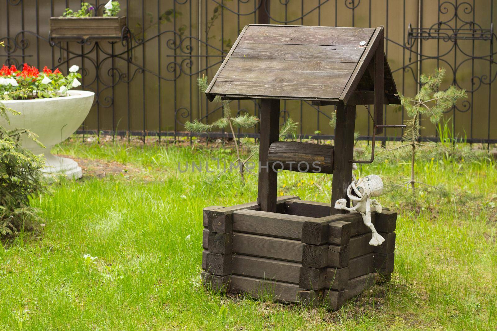 Wooden well to a picturesque place on green grass.