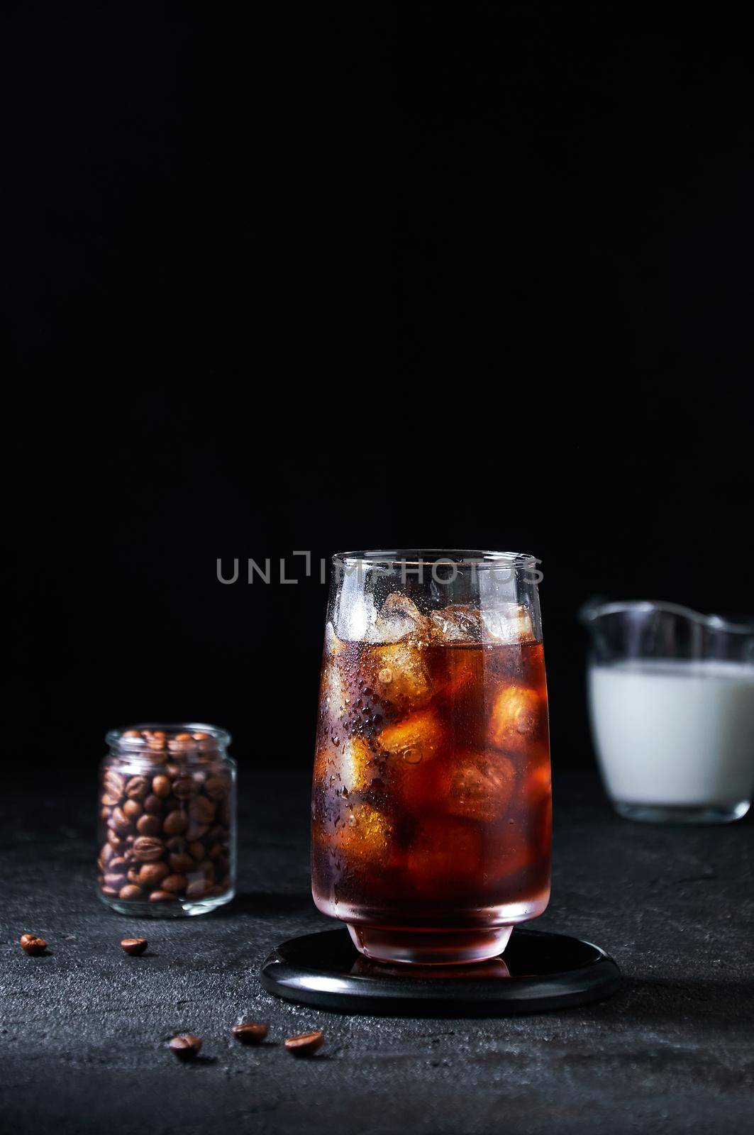 Iced Coffee in Tall Glass on Dark Background. Concept Refreshing Summer Drink.