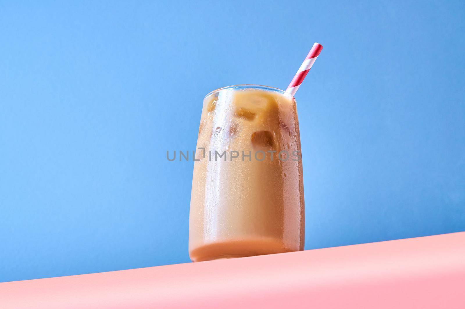 Iced Coffee with Milk in Tall Glasses on Pink Table and Blue Background. Trendy Hero View. Horizontal Orientation.