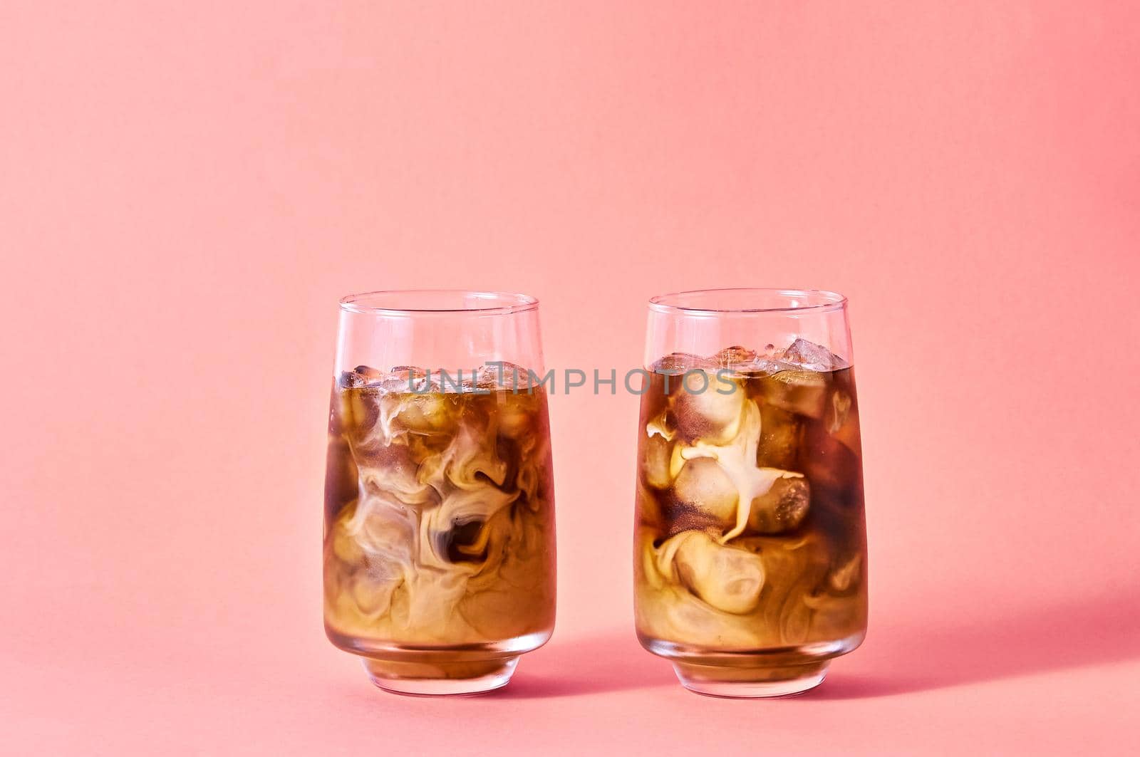 Iced Coffee with Milk in Tall Glasses on Pink Background. Concept Refreshing Summer Drink.