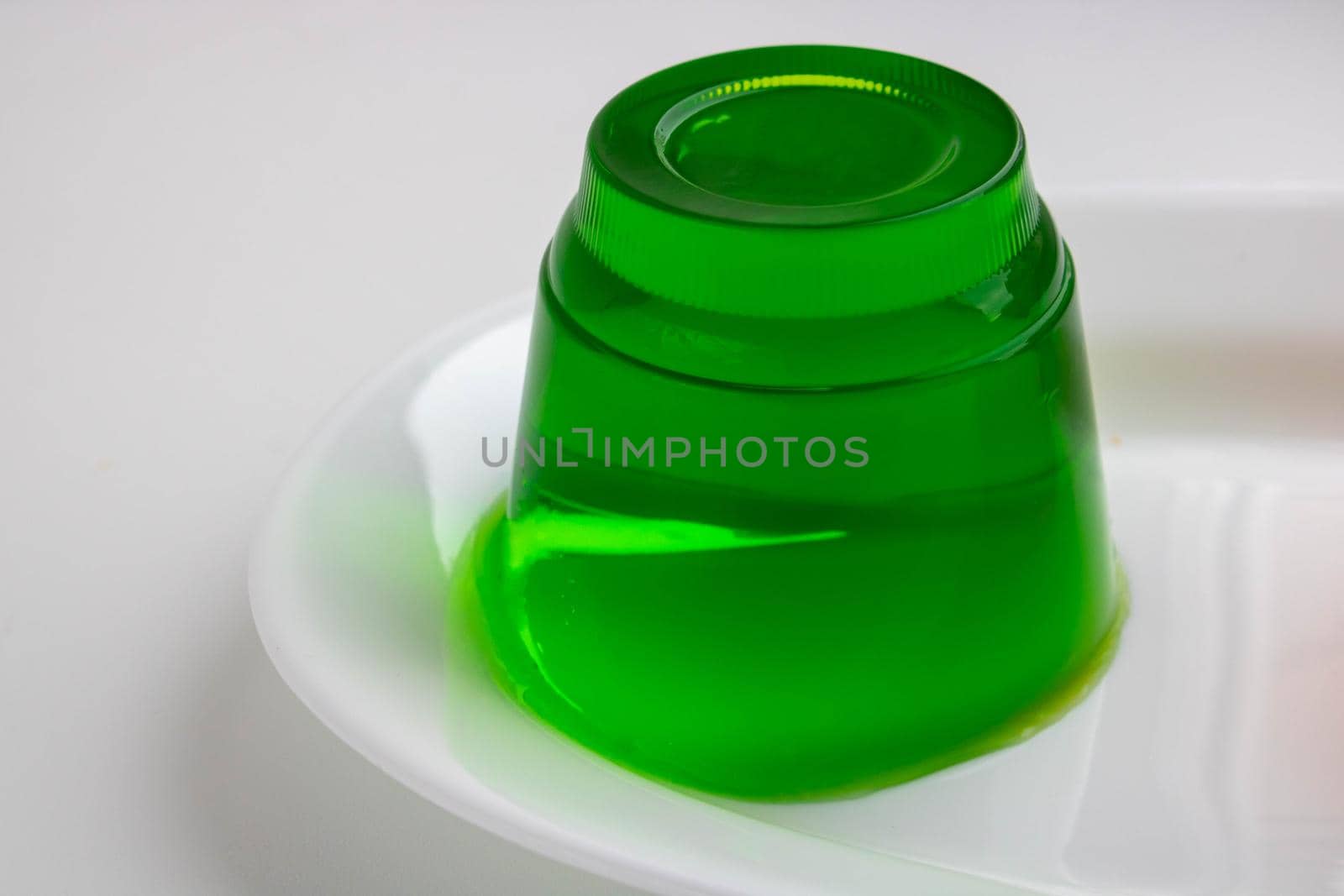 White plate with green kiwi jelly on a white background