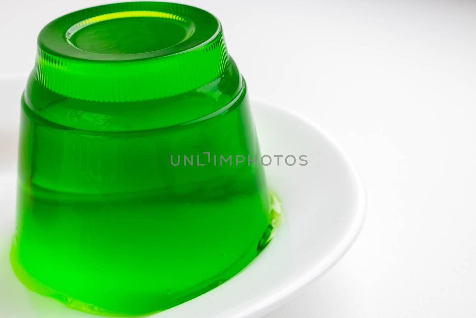 White plate with green kiwi jelly on a white background.