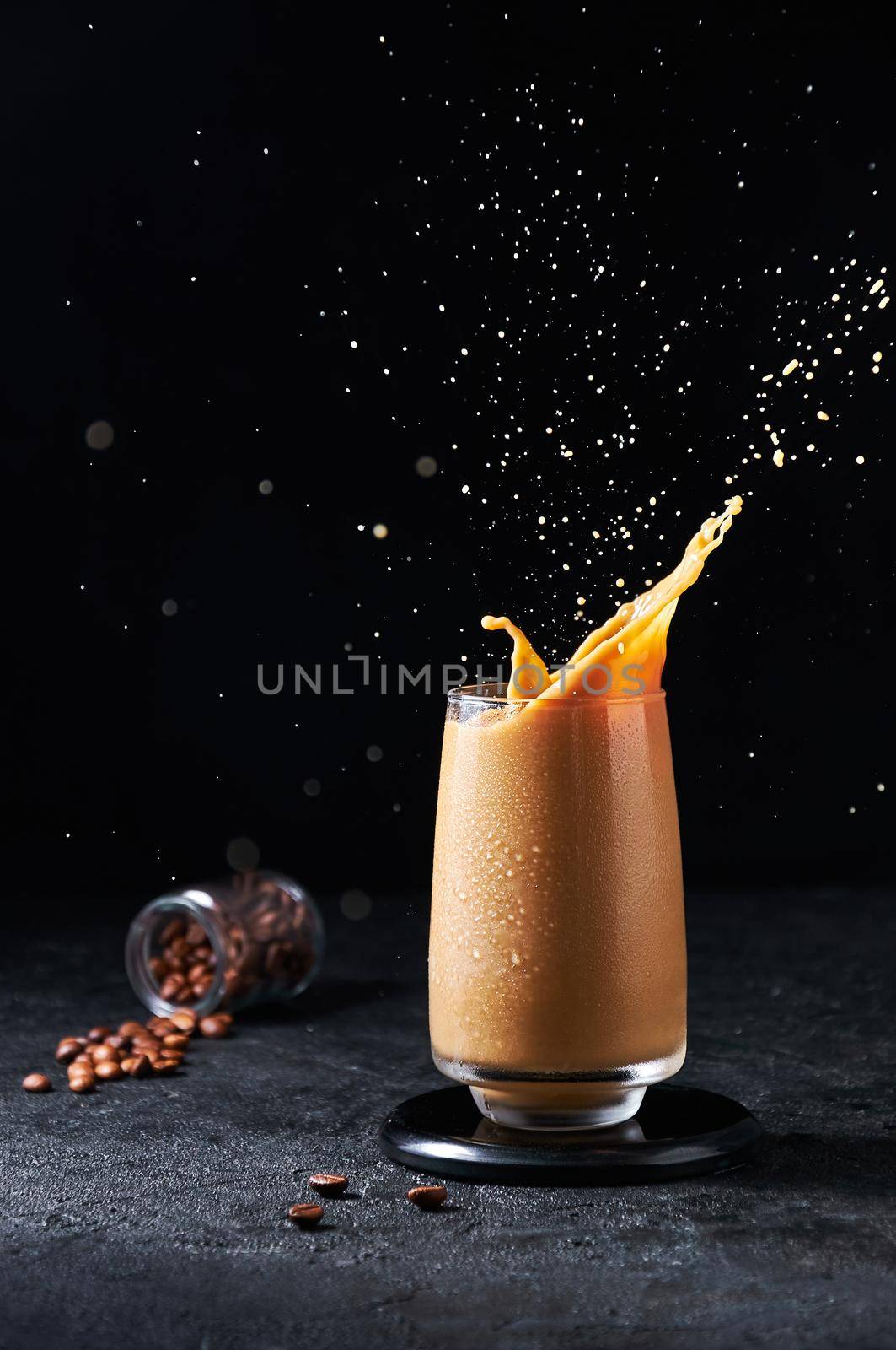 Cold Summer Drink. Iced Coffee with Splash in Tall Glass on Dark Background. Drinks in Motion.