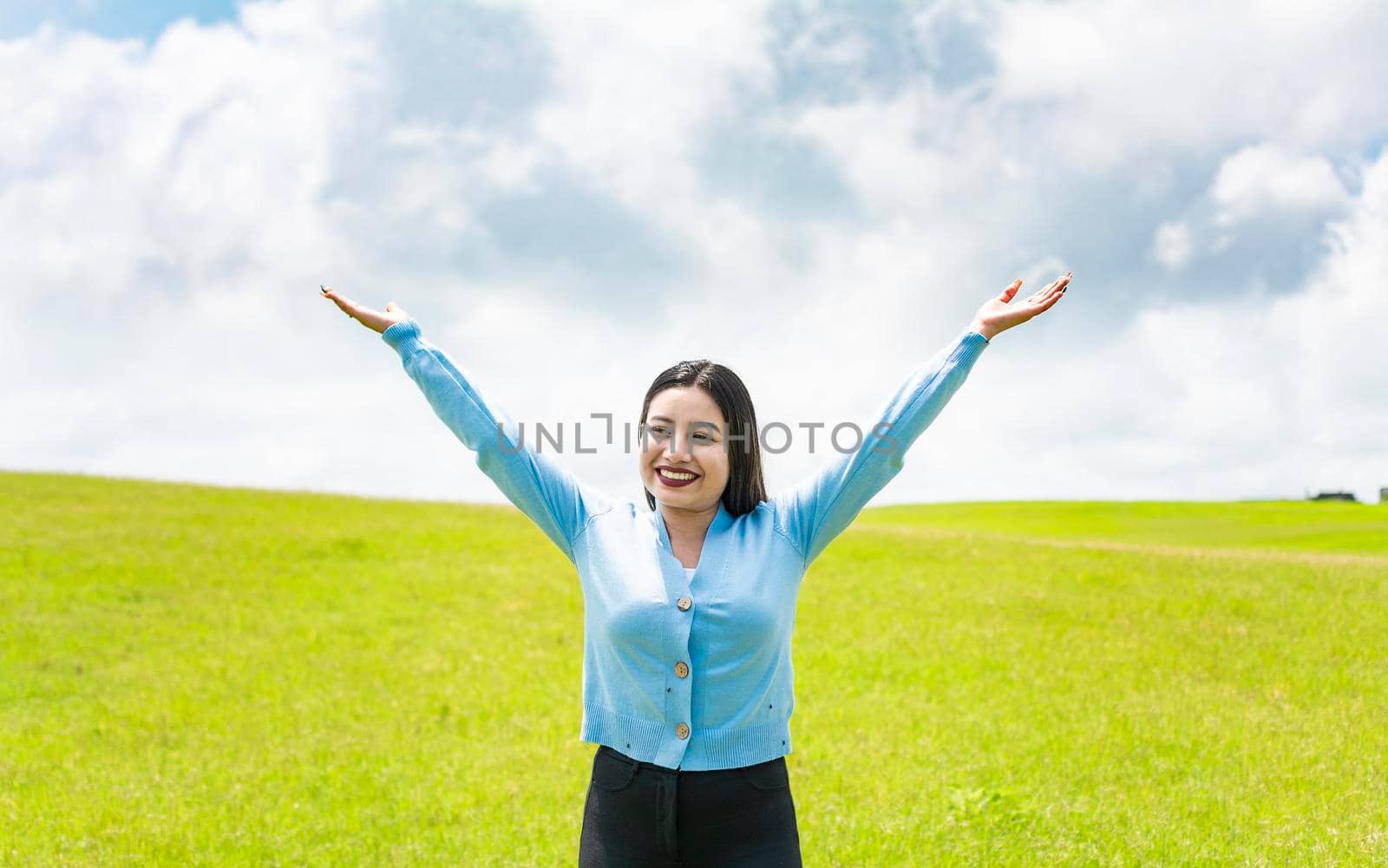 Attractive girl spreading her arms in the field, smiling young woman spreading her arms in the field, concept of free woman spreading her hands