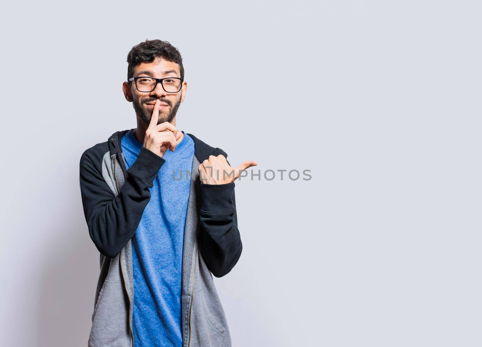 Mysterious person pointing to the side with his fingers on isolated background, Mysterious man pointing to the side with his fingers