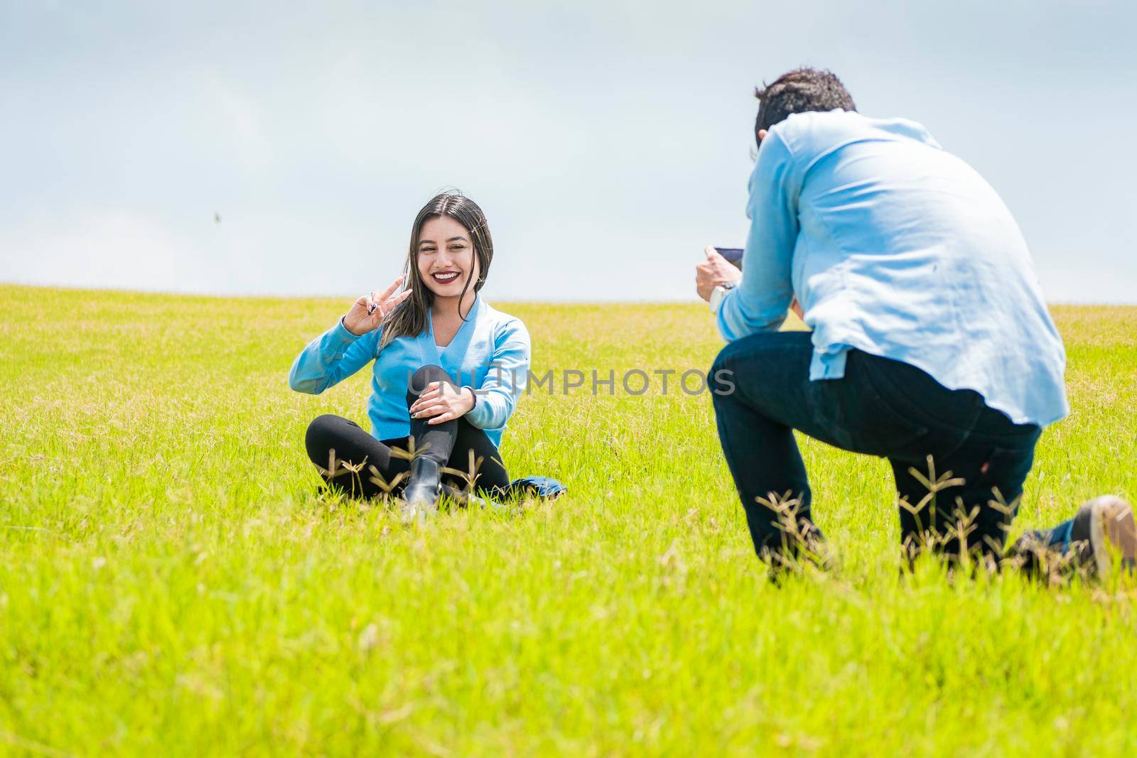 Two friends taking photos with the cell phone in the field, A guy taking a picture of a girl in the field, Boyfriend taking a picture of his girlfriend in the field by isaiphoto
