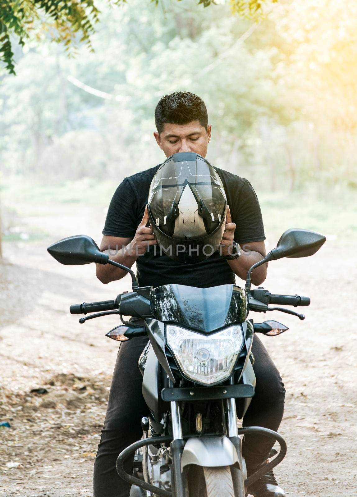 Man on motorcycle putting on helmet, motorcyclist putting on safety helmet, person on motorcycle putting on safety helmet