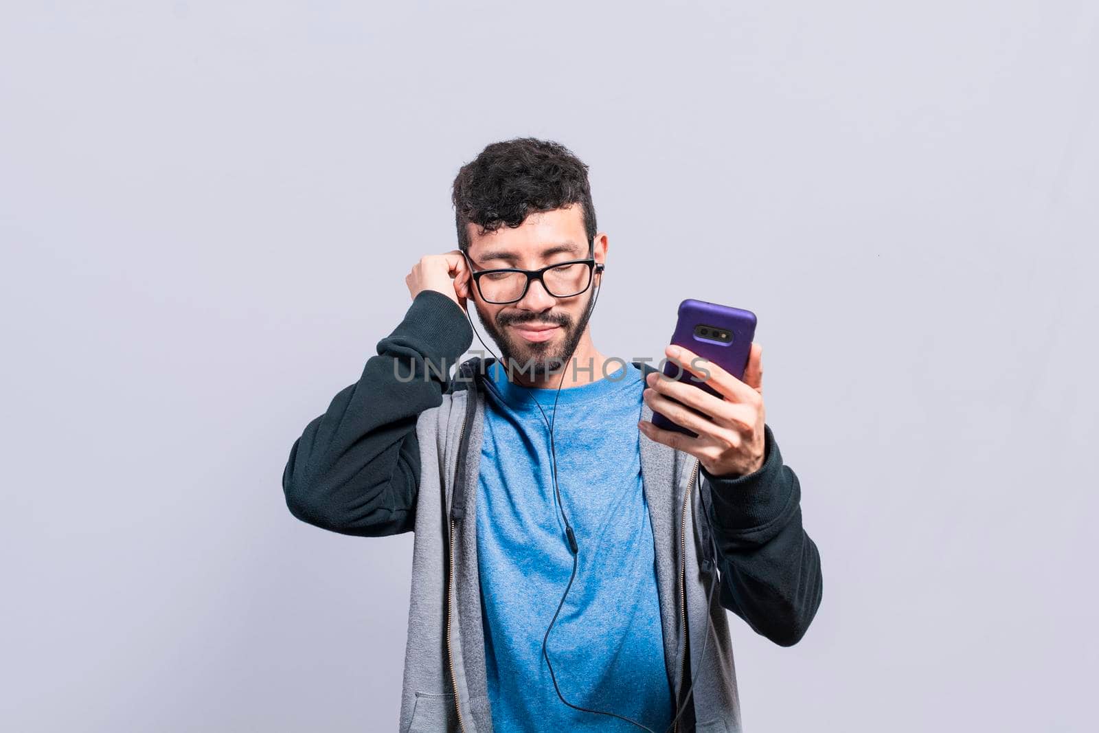 People enjoying music with headphones isolated, cheerful guy listening to music with his cell phone isolated, Person listening to music with his cell phone with headphones isolated