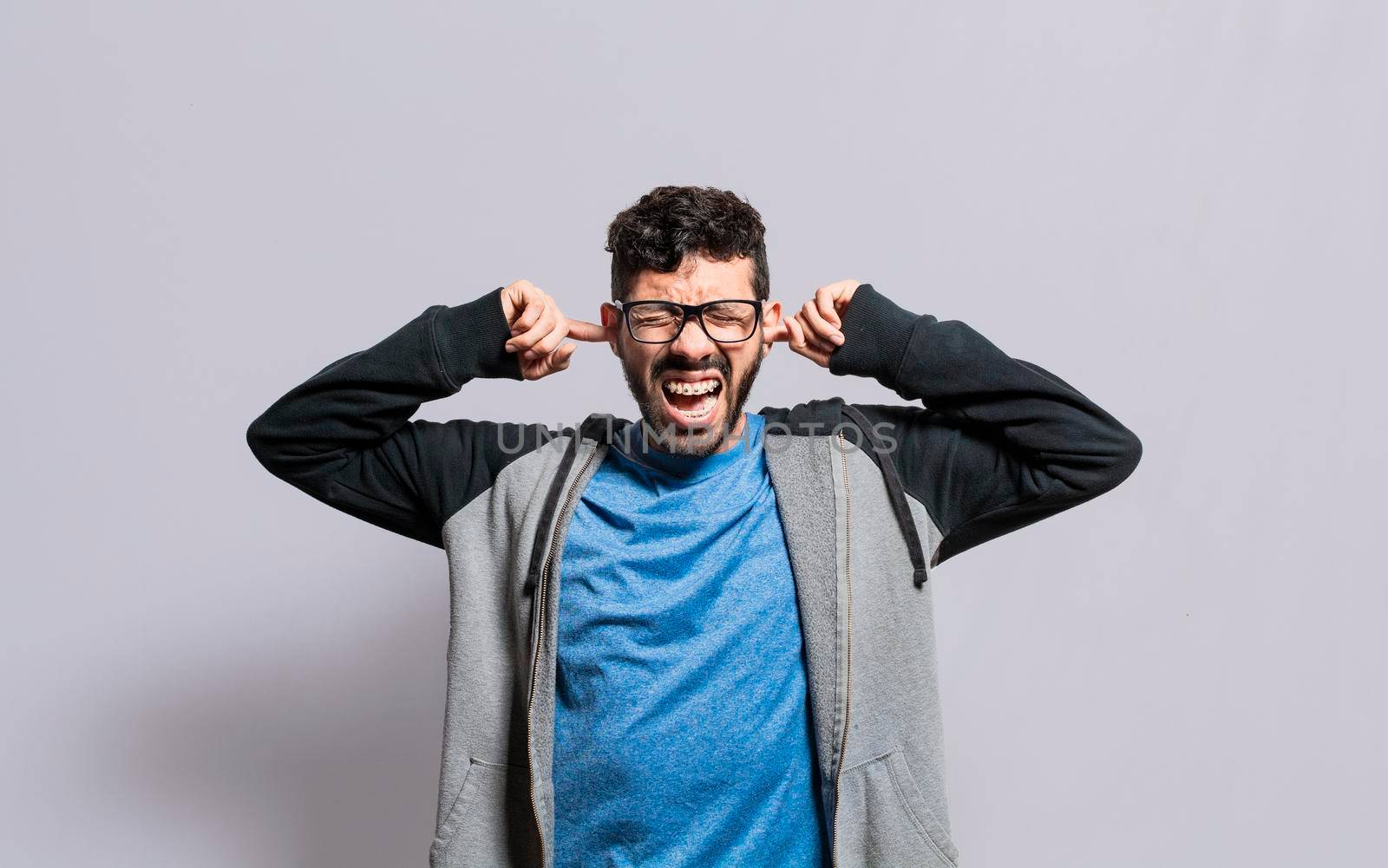 Irritated person screaming covering his ears, desperate person avoiding hearing bad news, stressed man screaming covering his ears