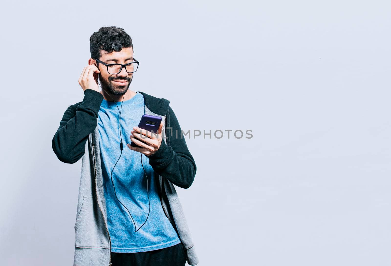 Person listening to music with his cell phone with headphones isolated, people enjoying music with headphones isolated, cheerful guy listening to music with his cell phone isolated