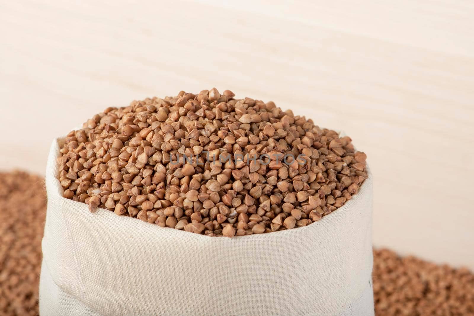 Buckwheat harvest. Poor agricultural harvests, food shortages, world hunger. A bag of buckwheat on a brown background by SERSOL