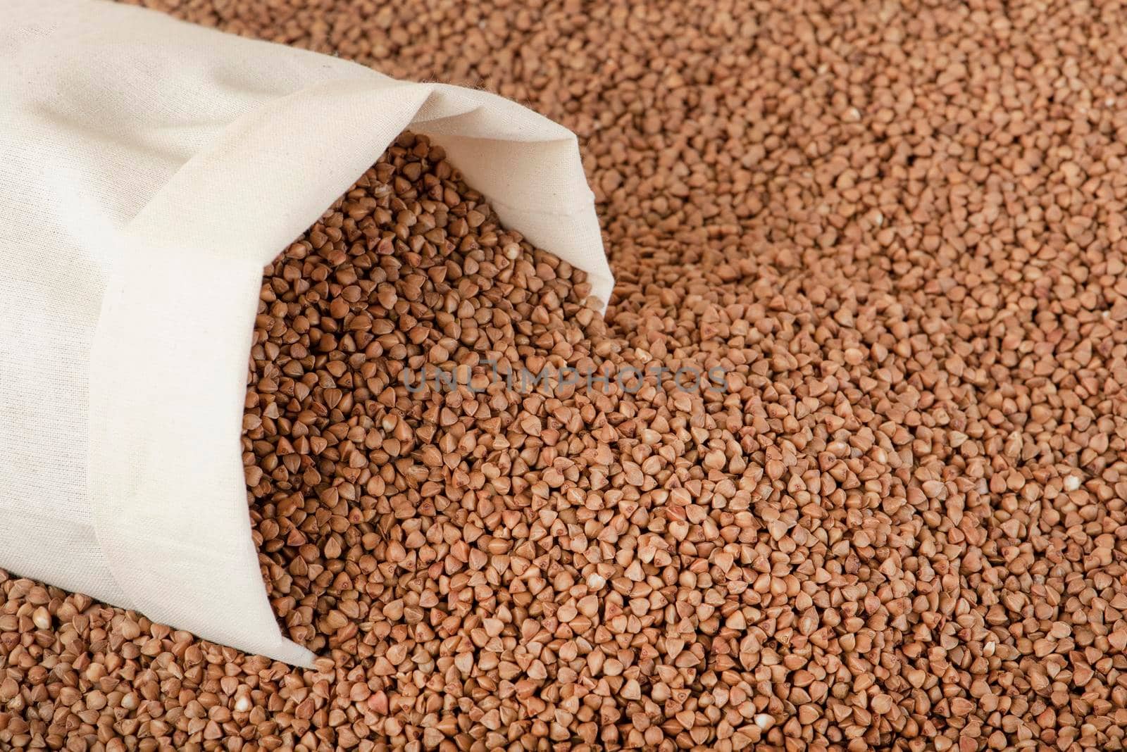 Buckwheat harvest. Poor agricultural harvests, food shortages, world hunger. A bag of buckwheat on a brown background by SERSOL