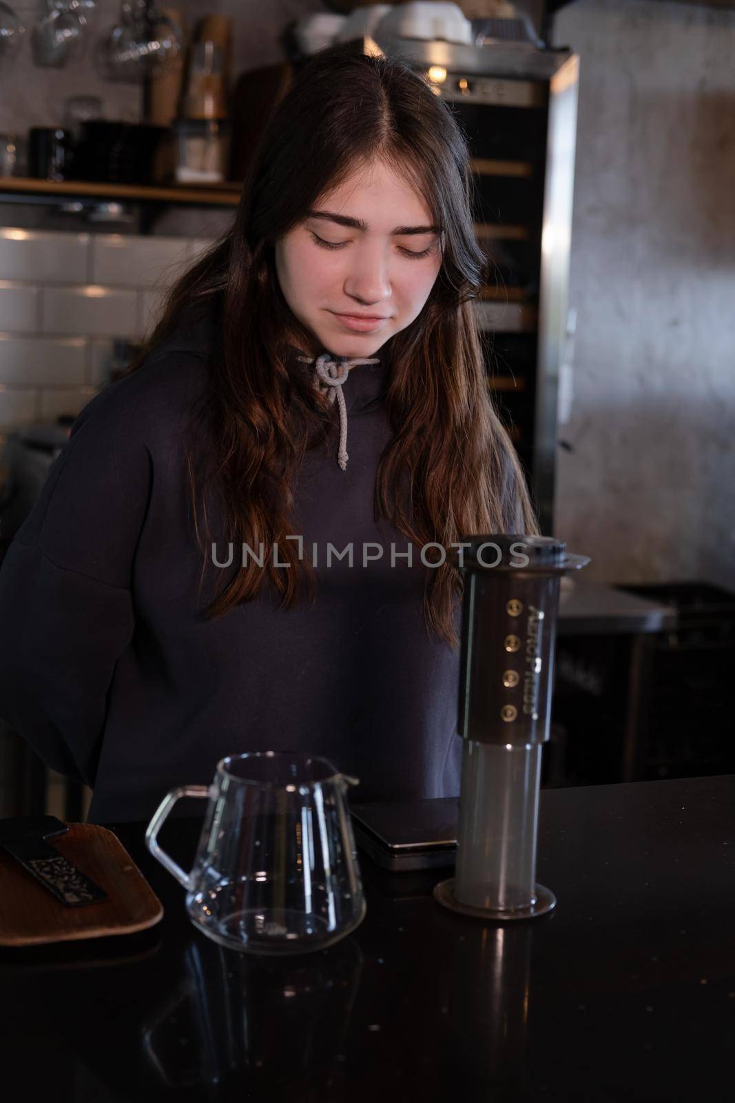 pretty brunette girl making aeropress coffee in modern coffee shop.