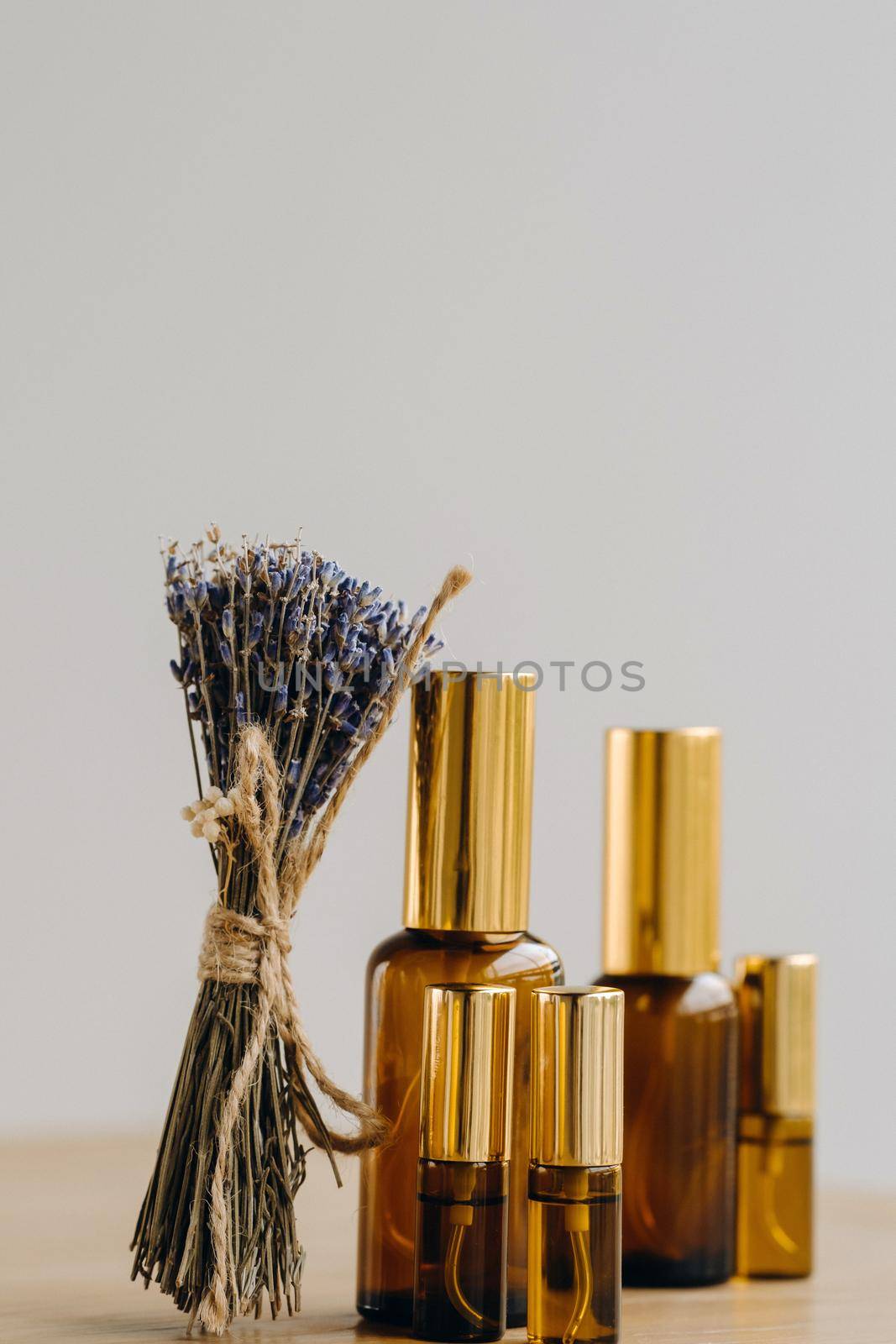 Essential oil in one bottle and dried lavender standing on the surface by Lobachad