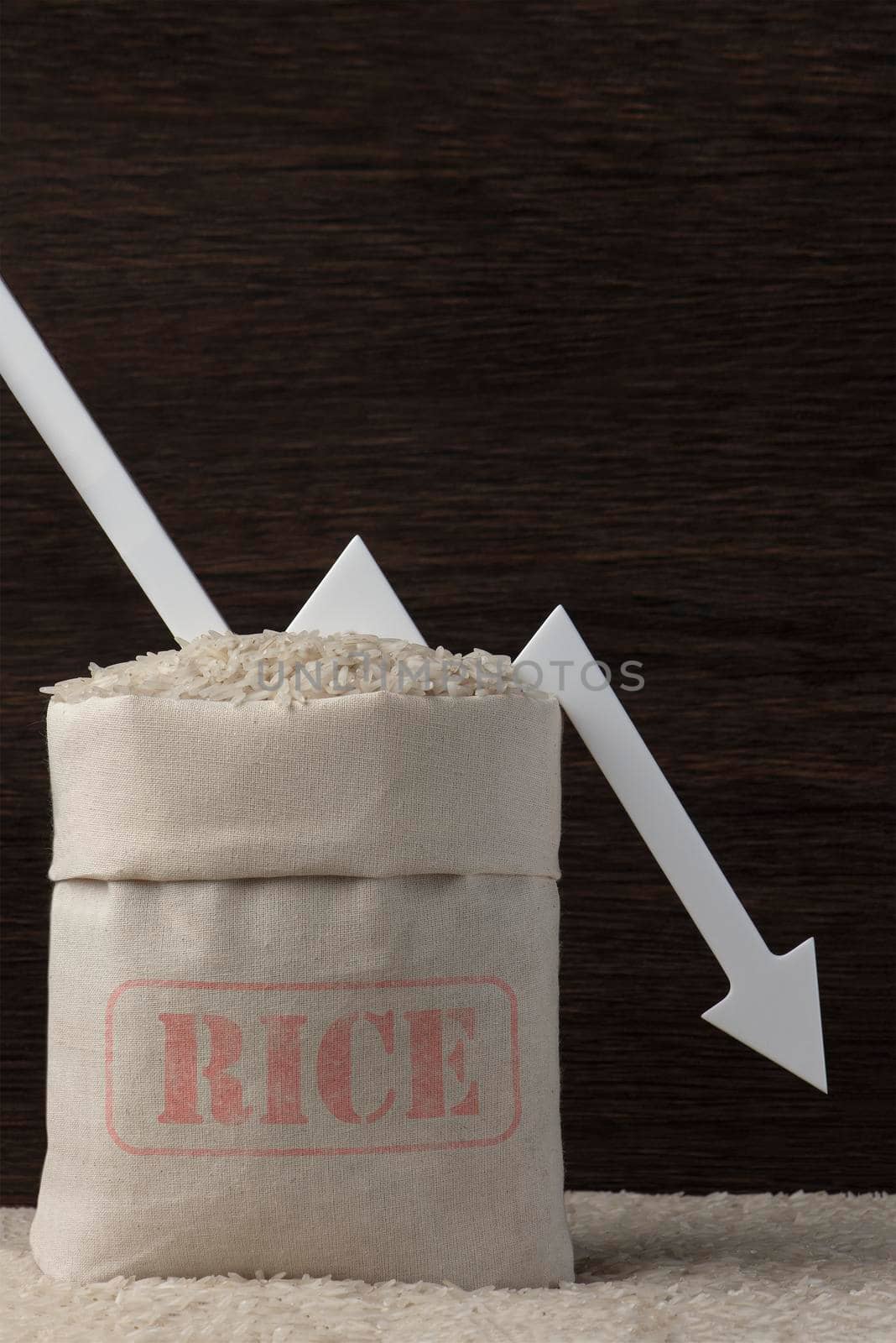 Rice harvest. Poor agricultural crops, food shortages, world hunger. A bag of rice on a brown background with a white arrow pointing down. by SERSOL