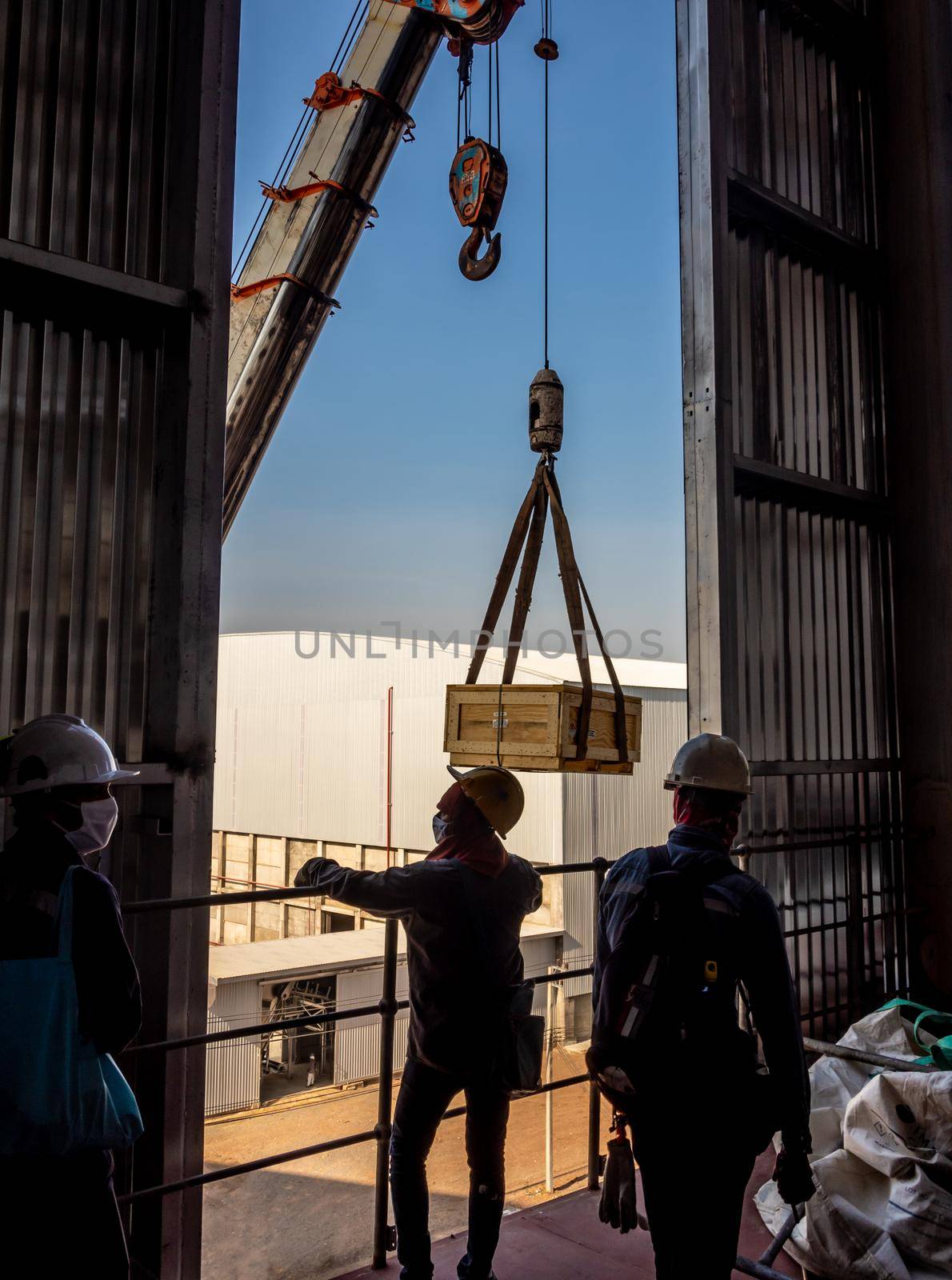 The crane carrying a wooden box of the radioactivity holder into the window on the factory floor