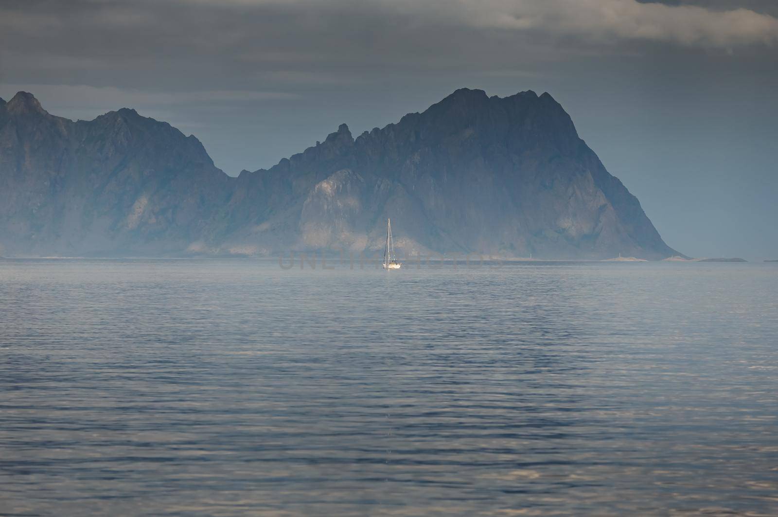 sailing yacht is on the horizon, norwegian seascape, rocky coast with dramatic skies, the sun breaks through the clouds, sheer cliffs, small islands illuminated by the sun. High quality photo