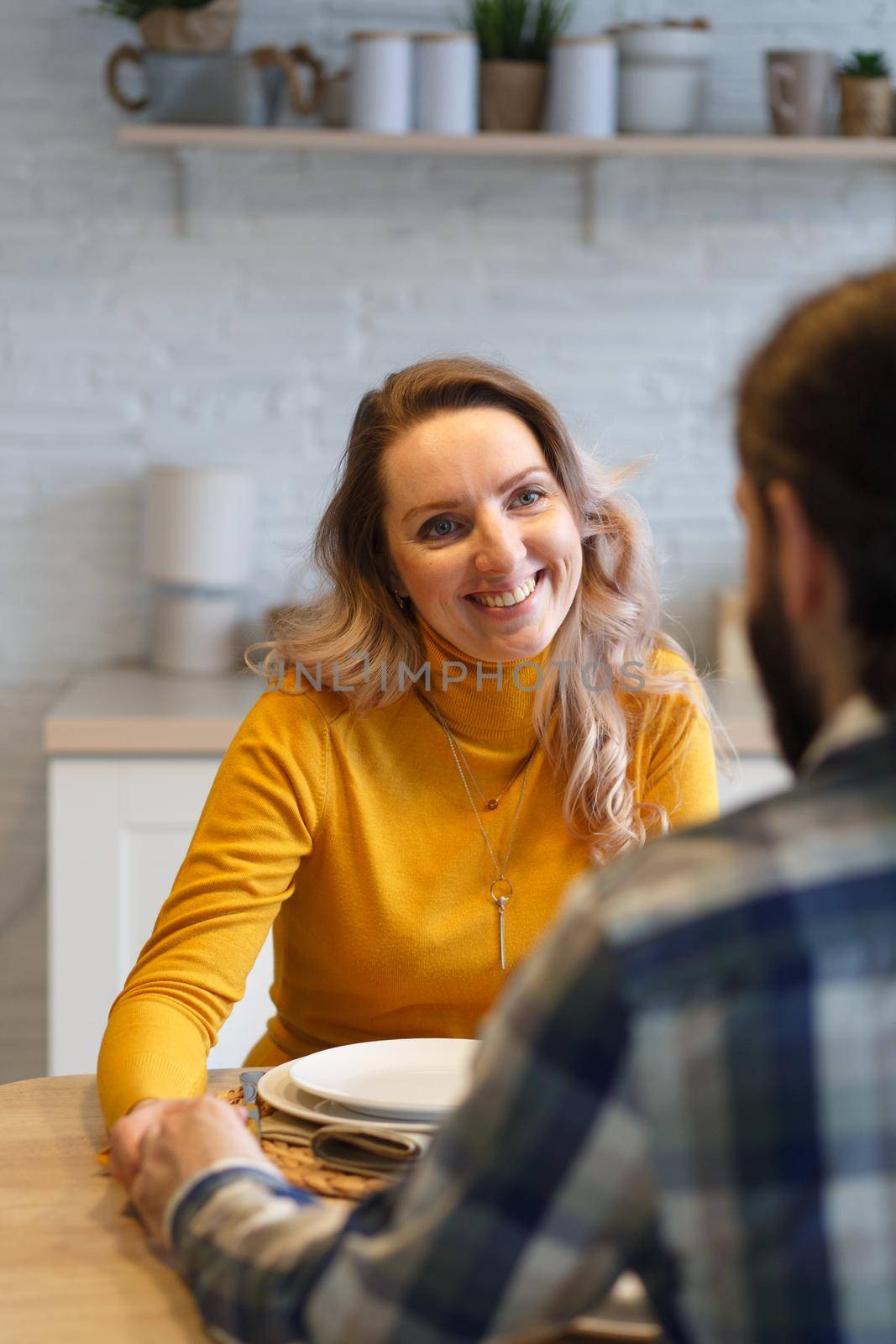 Beautiful couple having a conversation while looking at each other sitting at the table in a kitchen