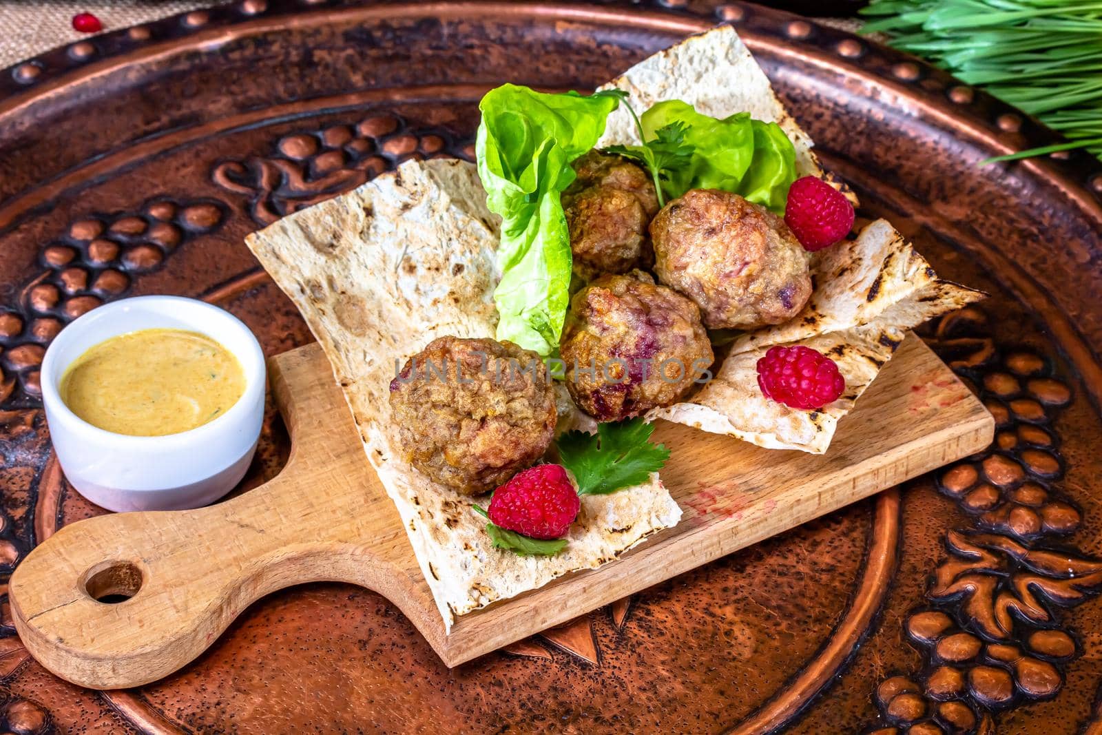 Grilled meatballs on pita bread with sauce by Milanchikov