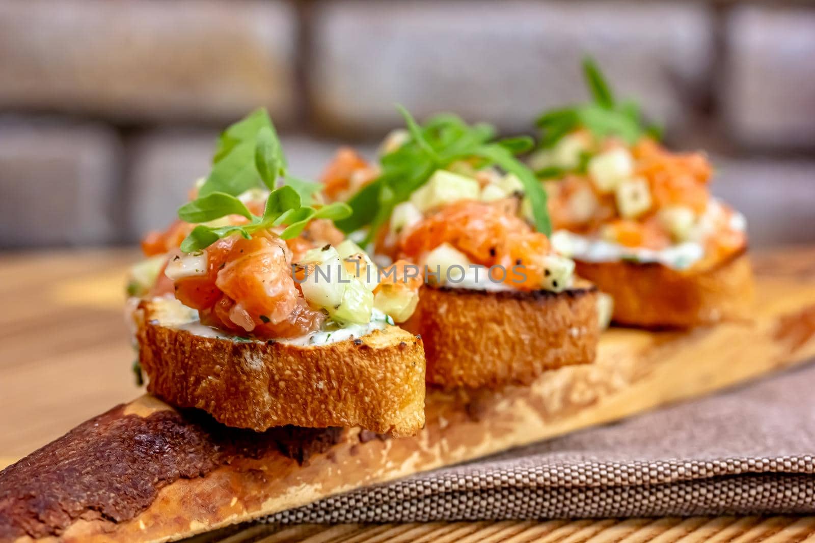 dry aged smoked salmon on the slices of bread and cream cheese sandwiches with cherry tomatoes and rocket salad.
